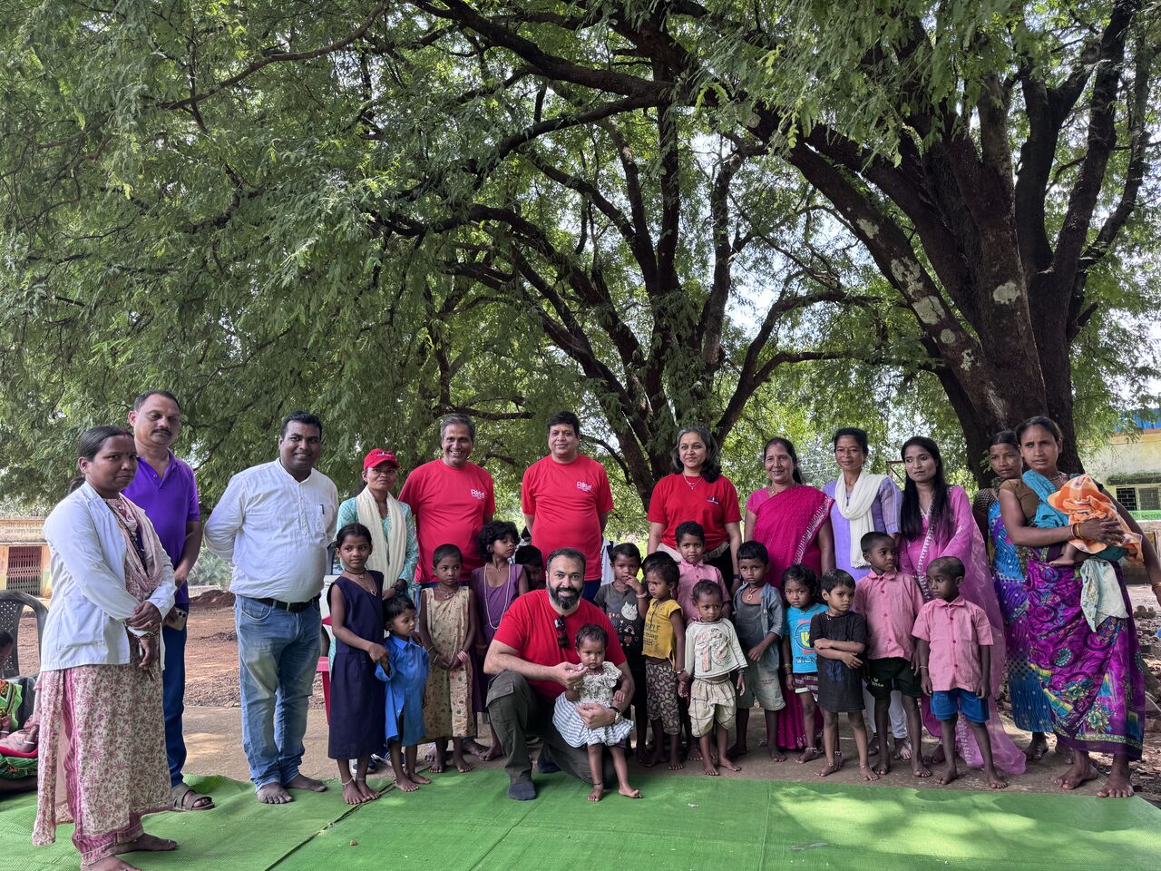 RAHI team with village children gathered under a large tree during the field visit