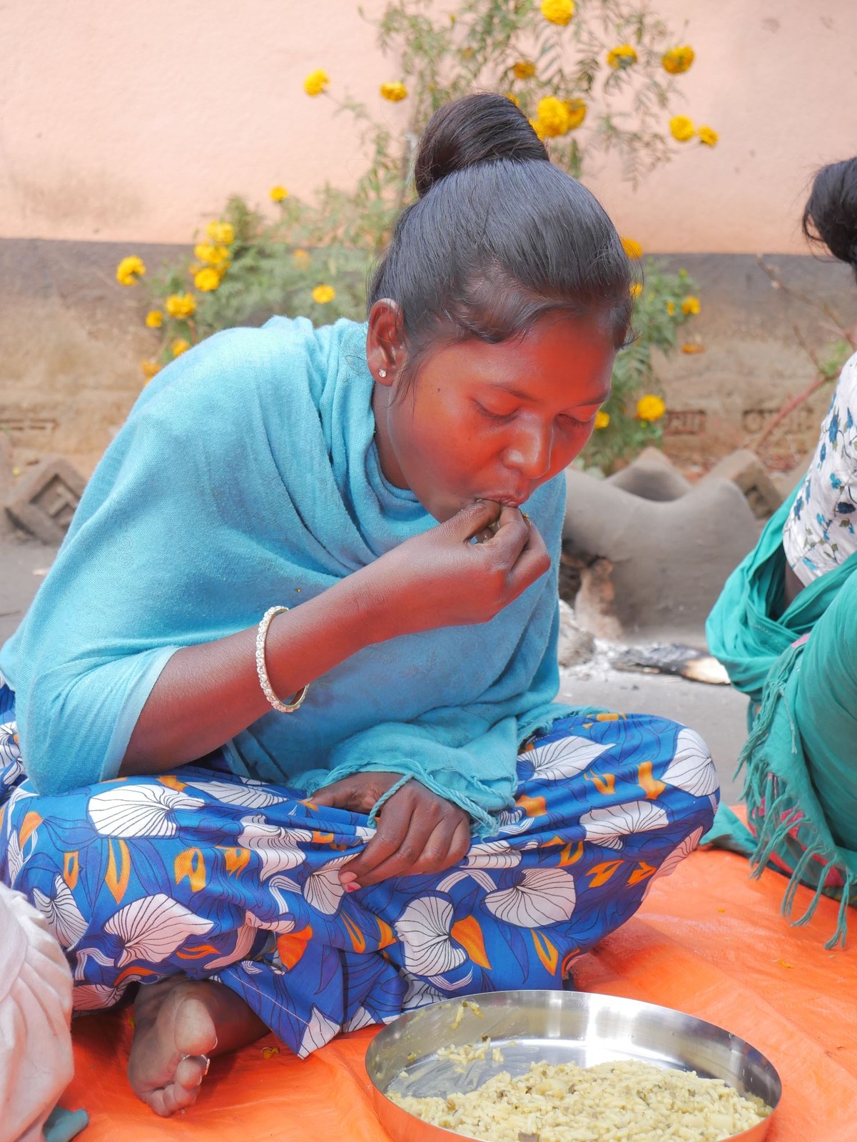 A mother eating a nutritious cooked meal at a Rise Against Hunger India Community Kitchen Centre