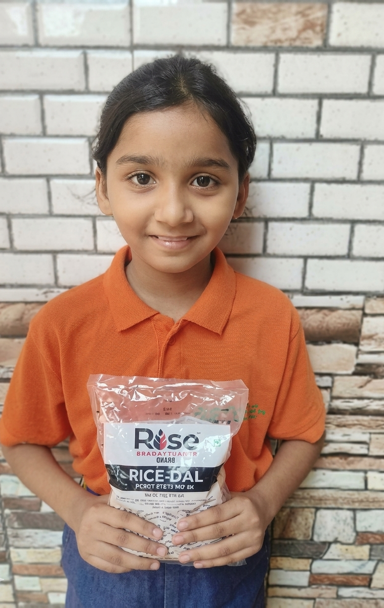 Aaradhya, a Grade 3 student holding a Rise Against Hunger India meal packet